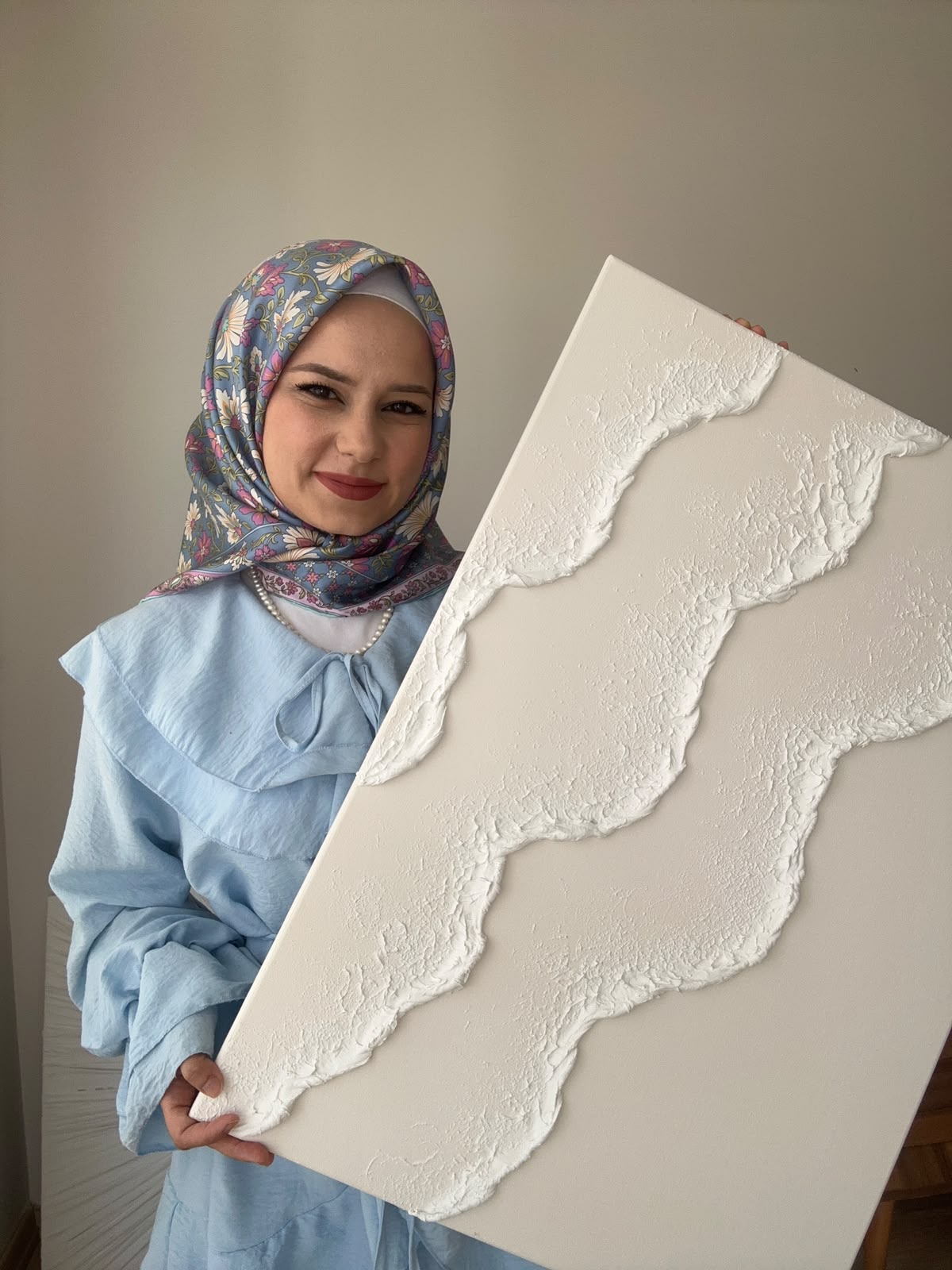 Büşra Koç, beyaz kabartmalı el yapımı eserini tutarken