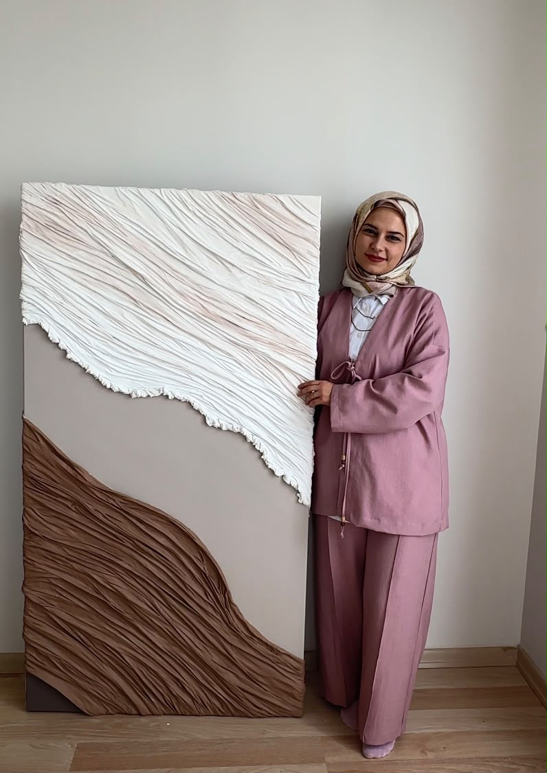 Büşra Koç, beyaz ve kahverengi dokulu büyük boy tablosunun yanında